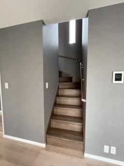 階段は床よりやや暗いウォールナットを採用。リビングから２階へ。